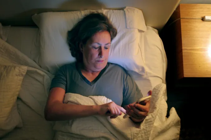 Picking up the phone to get a healthy lifestyle, shown by a woman in bed