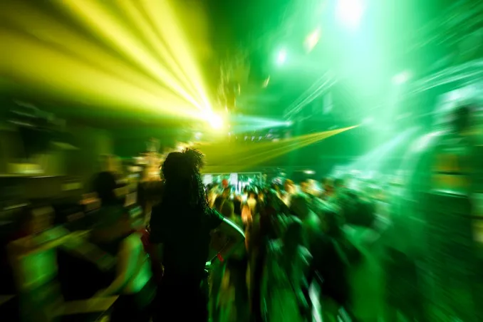 Green and yellow lights at a darkened rave point toward an answer to: does music glorify drug abuse