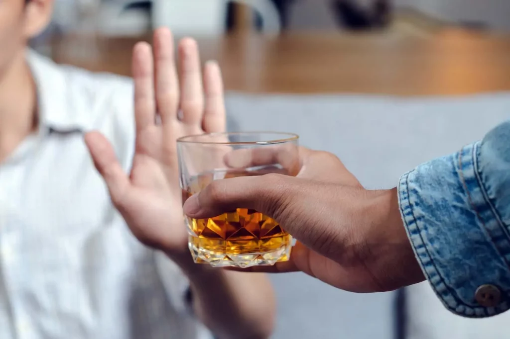 A hand pushes away a drink, to show the concept of giving up alcohol