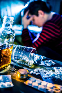 Alcohol Abuse and Alcohol Overdose | Alcohol Deaths By State | Find Addiction Rehabs | Pile of pills next to whisky bottle and man indulging in alcoholism