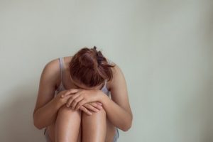 Ativan Addiction Withdrawal, a Young woman sitting on the floor with her knees pulled into her chest her hands resting on her knees and her head down resting on top of her hands.