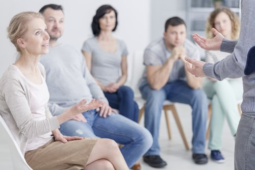 Alcoholic - Group of people sits in therapy listening to an alcoholic talk about their recovery.