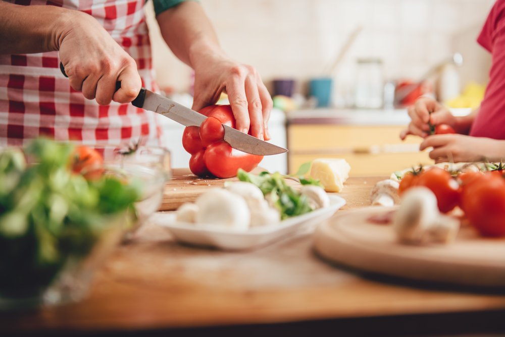 Anxiety - Health eating will reduce anxiety. Photo of a man slicing a red bell pepper on a cutting board. 3 tomatoes and some garlic sit on the counter also.