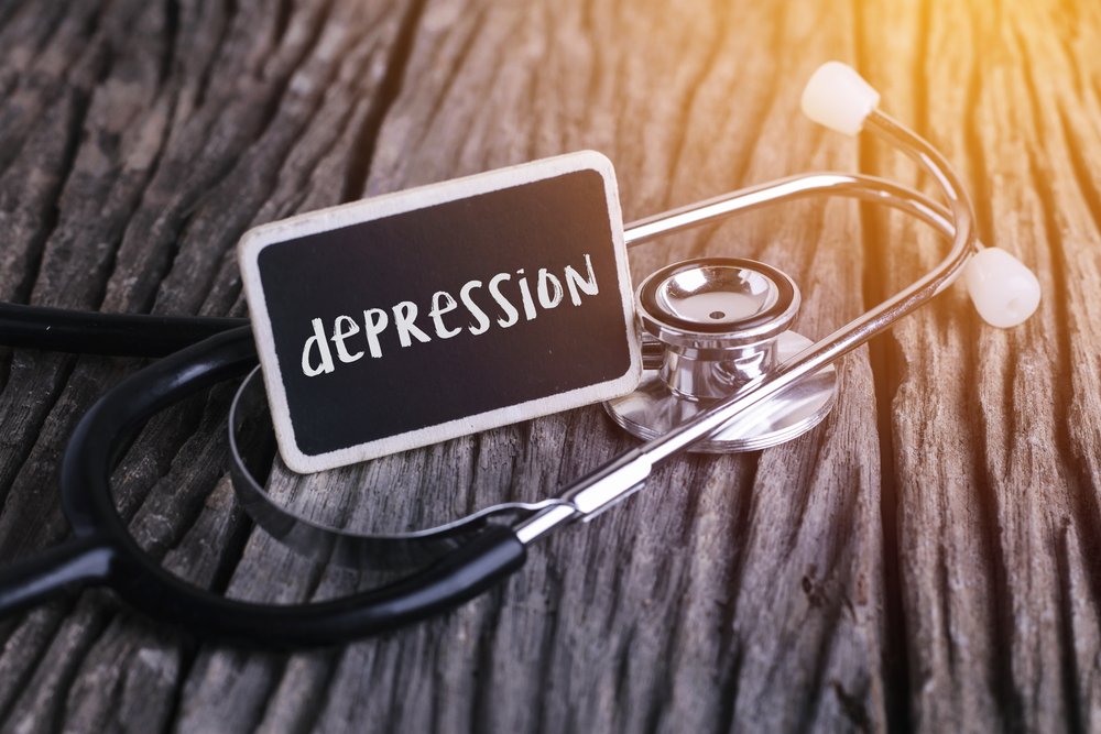 Dual Diagnosis - Small name tag that looks like a chalk board with "depression" written on it sitting inside a doctors stethoscope.