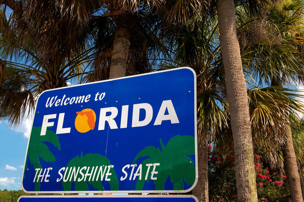 Florida Treatment Model for Addiction, a Welcome sign for the stats of Florida that you would see driving across the state line into Florida the text on the sign reads 'Welcome to Florida the Sunshine State" with several palm trees growing behind the sign.