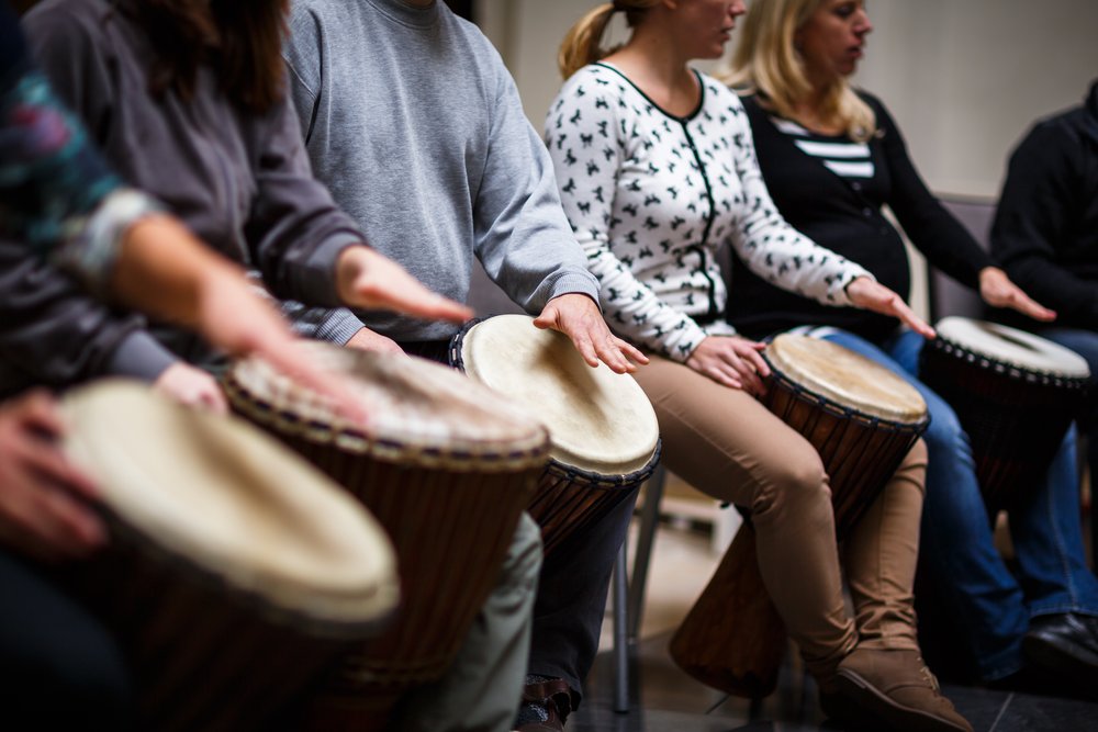 Music Therapy - Group of people sit and play the bongo drums during their addiction treatment.