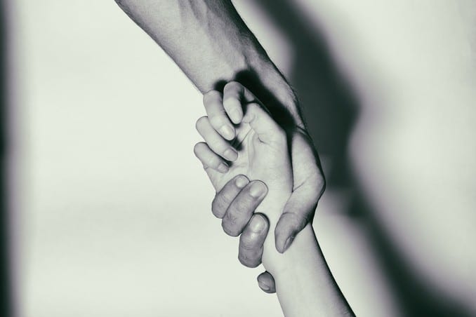 A hand lifting another person up, to demonstrate the best treatment for addiction