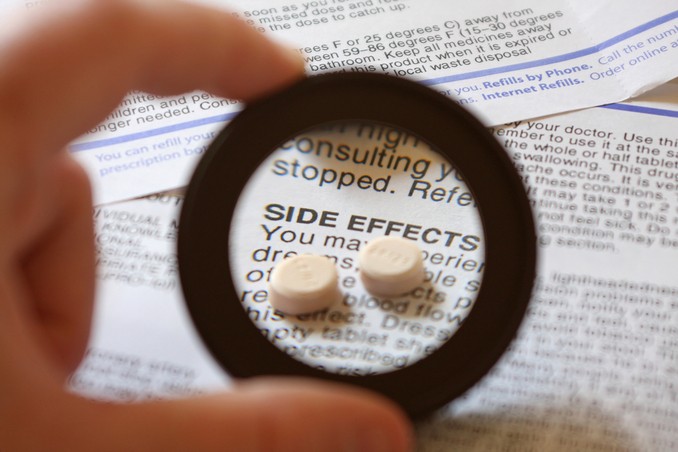 A handheld magnifying element looks over a book with side effects highlighted and Tramadol pills above the lettering