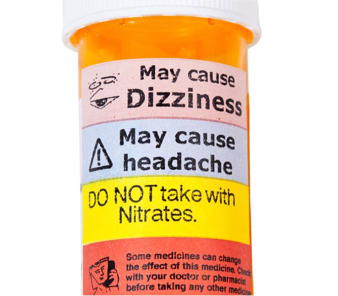 Close-up of prescription bottle with warnings, may cause 'dizziness,' etc.