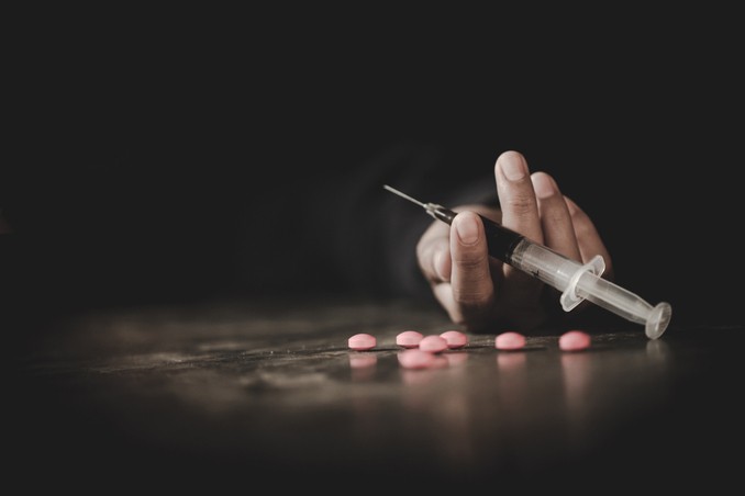 A hand grasping a syringe demonstrates the signs of drug addiction