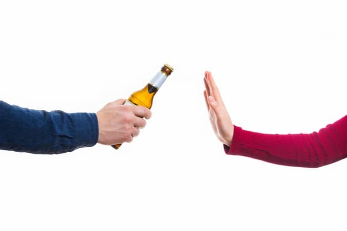 One hand offering another a beer, with person refusing to illustrate substance abuse prevention