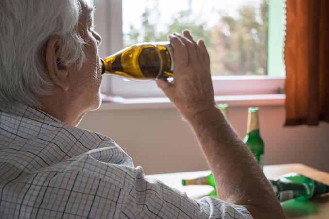 Senior man, drinking alone, example of common symptoms of alcoholism