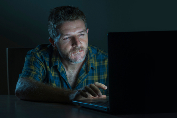 The need for sex addiction therapy, as shown by a lonely man staring intently at his computer screen in the dark