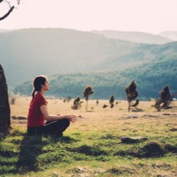 Woman meditating in a field, to illustrate the potential for healing with experiential therapy