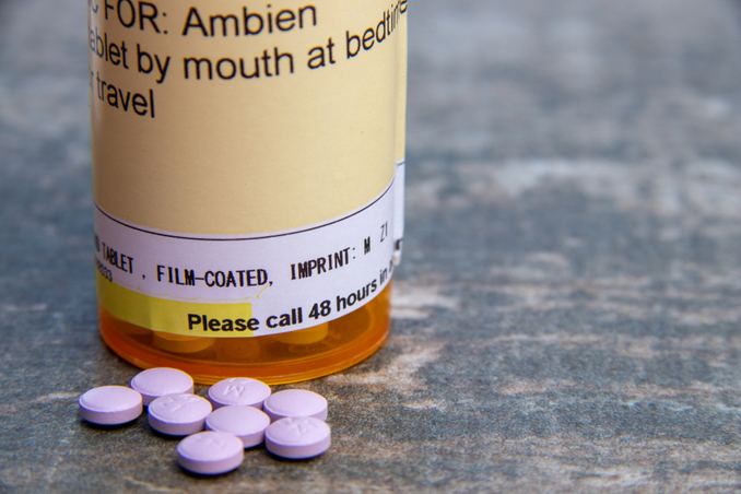 A bottle of Ambien pills in foreground, to demonstrate beginning of 'How to Quit Ambien'