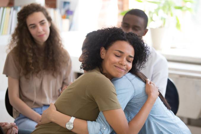 Young woman embracing counselor in group therapy