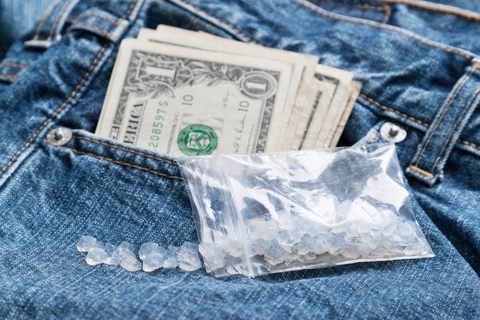 Blue jeans and $1 bills coming out of a pocket, to show the concept of cheap, pure meth responsible for meth overdoses rising dramatically