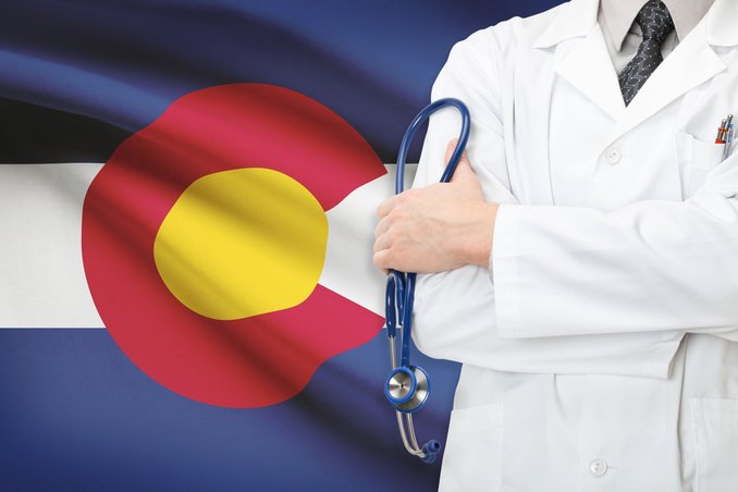 Physician in front of Colorado flag, to illustrate the wisdom of finding out more about drug and alcohol rehab in Colorado