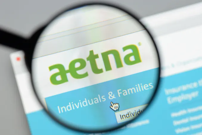 A magnifying glass shows the aetna name, with the idea of substance use disorder treatment coverage
