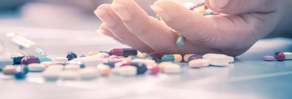 An outstretched hand with pills surrounding shows the signs of Dilaudid Addiction