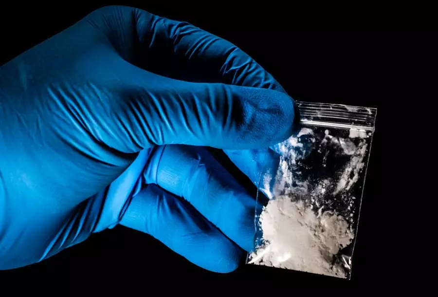 A gloved hand holds up a bag of white powder, to show the importance of fentanyl detox near me