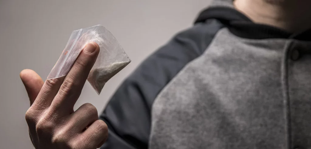 Fentanyl Addiction: A hand holding bag of powder to show the dangers of fentanyl