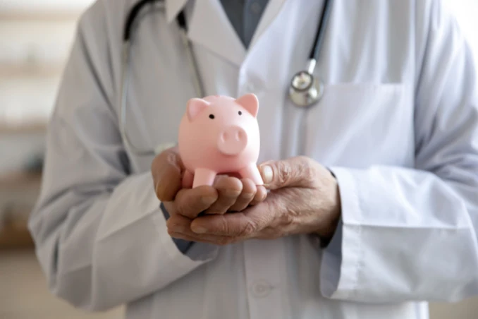 Doctor with a piggy bank shows the concept of Anthem drug rehab costs