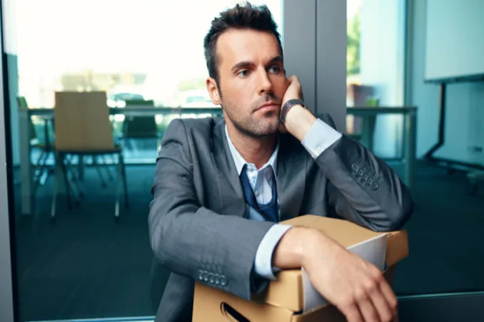 Using COBRA for rehab coverage after job loss, as shown by man losing his job with box of work belongings