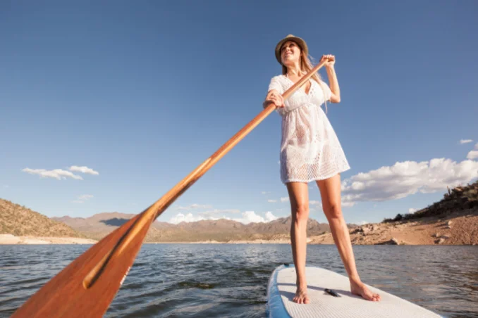 A woman on paddleboard shows the concept of fun in addiction recovery in Arizona