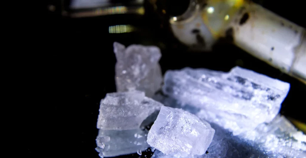 Shards of crystal meth and a pipe in background show the concept of what meth looks like
