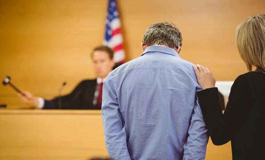 A man in need of court ordered rehab services stands before a Judge, not knowing that Find Addiction Rehabs can help him out of handcuffs and into recovery