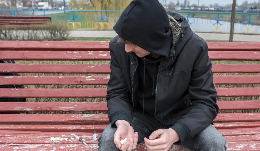 A man on a park bench looks at drugs as a concept pic for harm reduction efforts