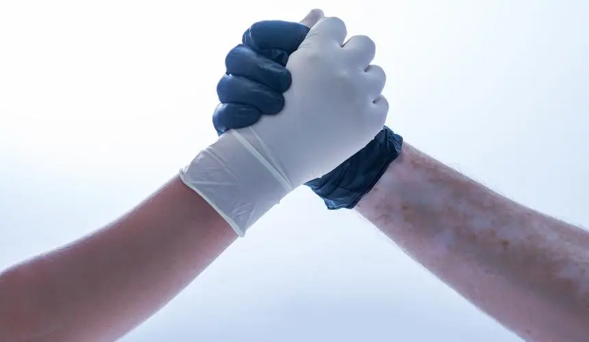 Clasped hands in gloves show the concept of the harm reduction movement